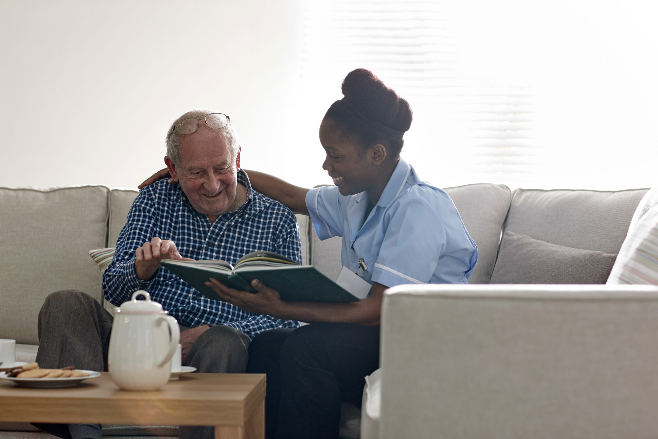Happy senior man with carer reading a novel together
